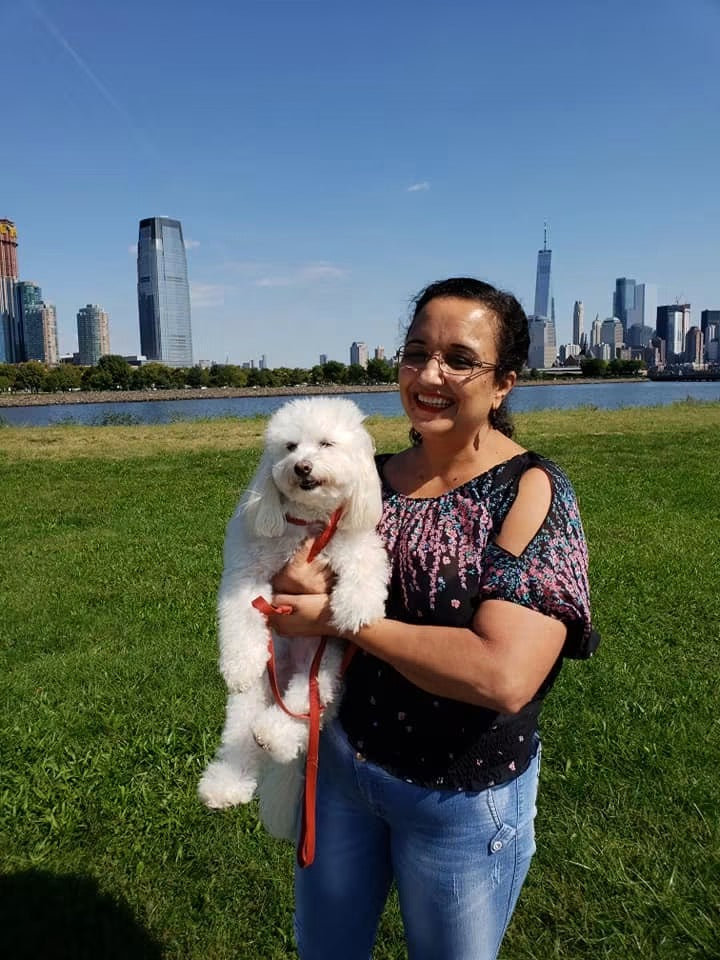 Geralda holding Luna outdoors near the New York City skyline.
